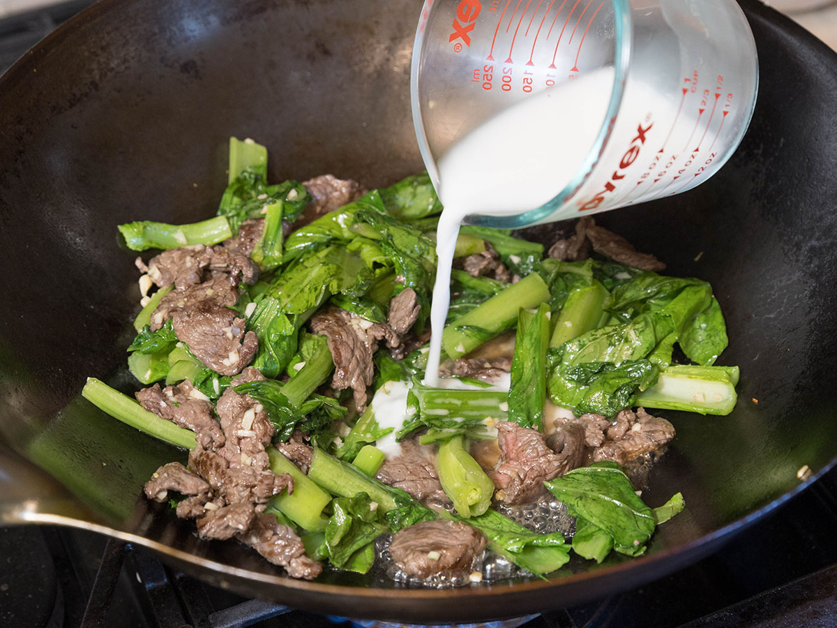 Adding cornstarch mixture to the beef and greens.